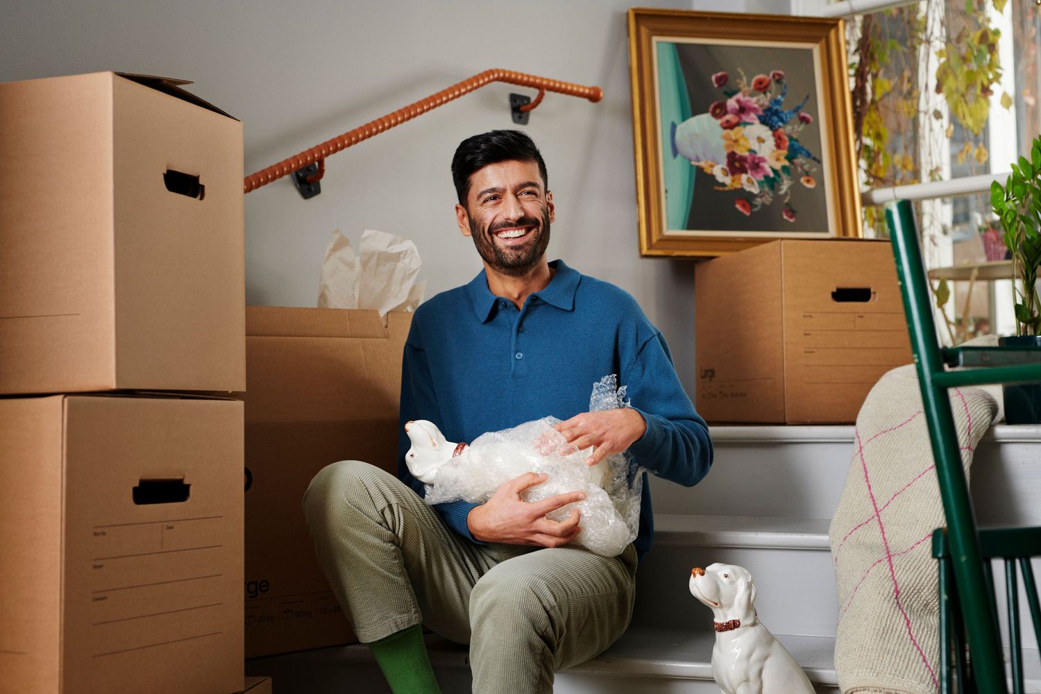 En person sittandes i en trappa som packar upp flyttkartonger