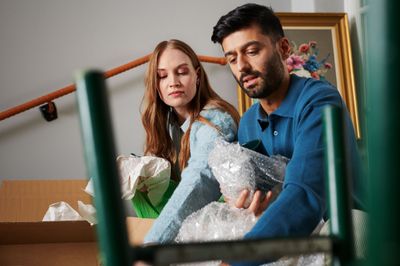 Två personer som packar tittar ner i en flyttkartong